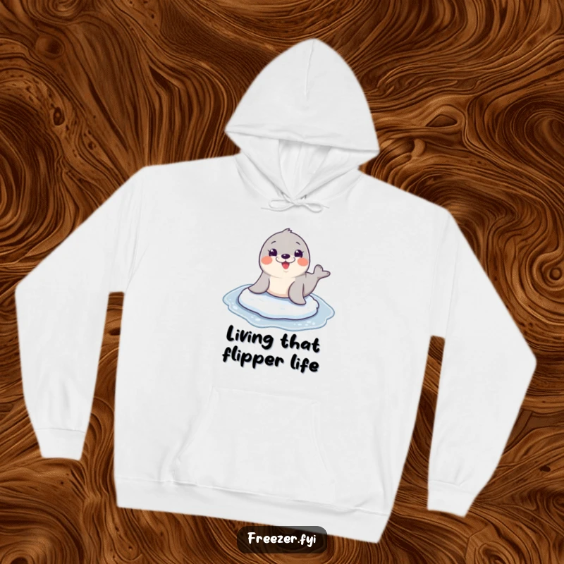 Funny seal character mid-slide on a frozen surface, wide joyful grin, on a warm and humorous hoodie.